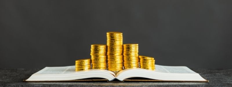 Does a book editor work for love or money? Gold coins piled on top of an open book